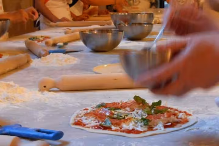 Hands preparing fresh pizza with basil and mozzarella in a Florence cooking class, showcasing authentic Italian cuisine.