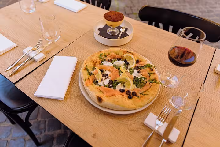 Gourmet pizza with olives and lemon paired with red wine and tiramisu at a Piazza Navona cooking class in Rome.
