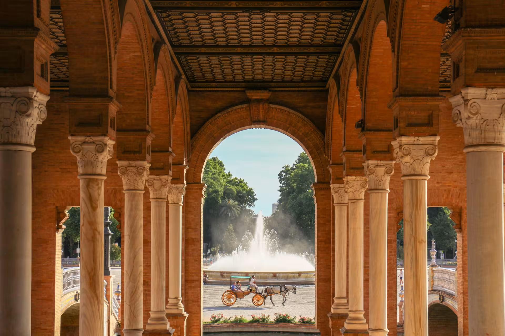 Plaza de España Seville archway framing fountain and horse carriage, highlight stop on free walking tour