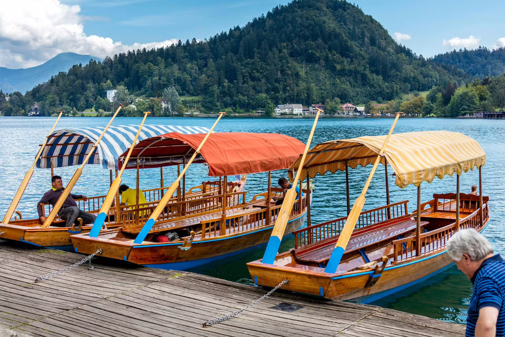 Colorful pletna boats moored at Lake Bled pier, Slovenia, for the summer tour boat ride experience