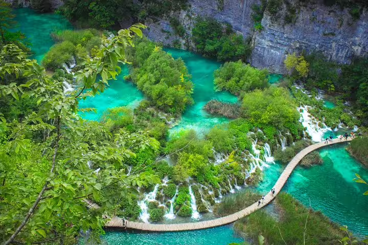 Wooden boardwalk over turquoise pools and waterfalls at Plitvice Lakes National Park, private day trip from Split