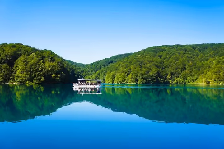 Boat cruising a turquoise lake in Plitvice Lakes National Park on a private tour from Split to Zagreb