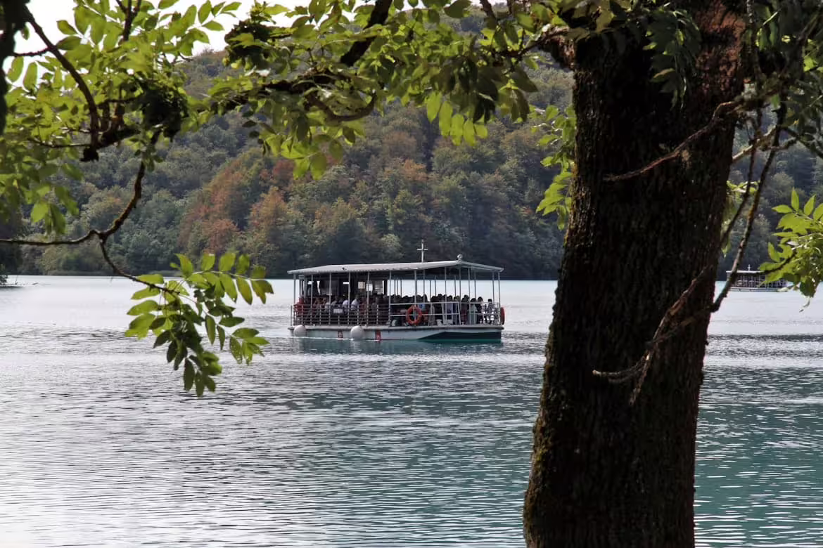 Electric boat crossing on Plitvice Lakes National Park guided group tour, scenic lake and wooded shore