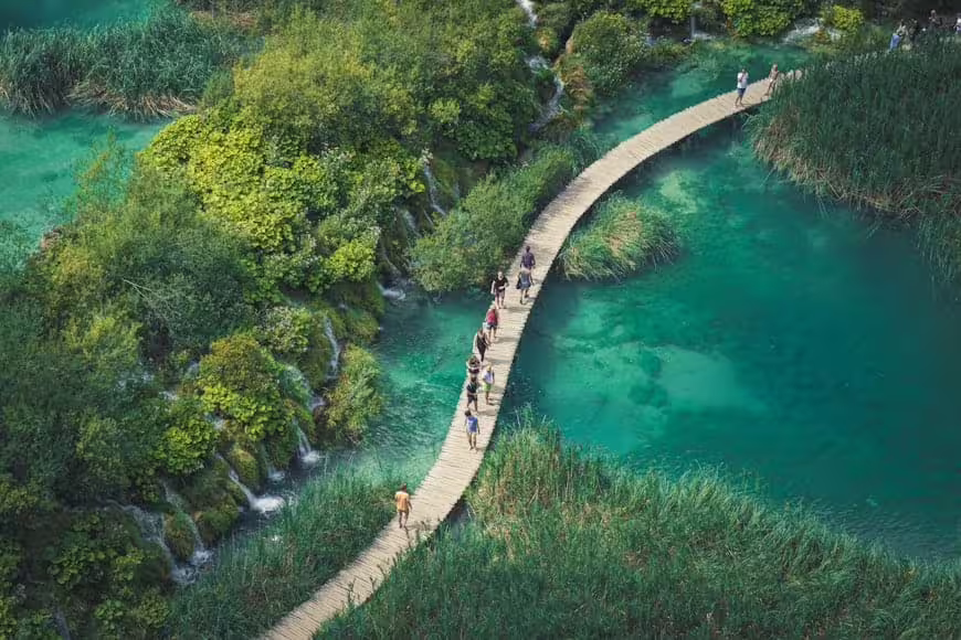 Guided group tour on Plitvice Lakes boardwalk over turquoise water and waterfalls in Croatia