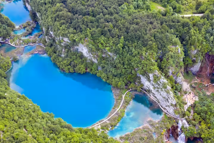 Aerial view of Plitvice Lakes turquoise waters and waterfalls, Croatia, with boardwalk route on train and boat tour