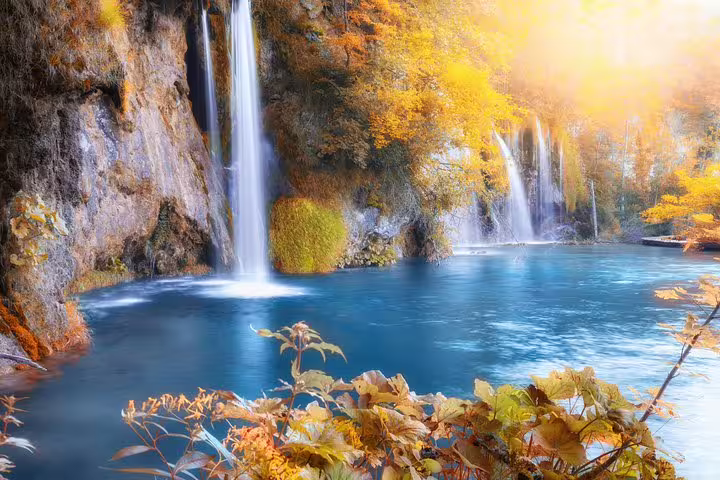 Waterfalls cascading into a blue lake at Plitvice Lakes National Park on a day tour from Zadar and Biograd