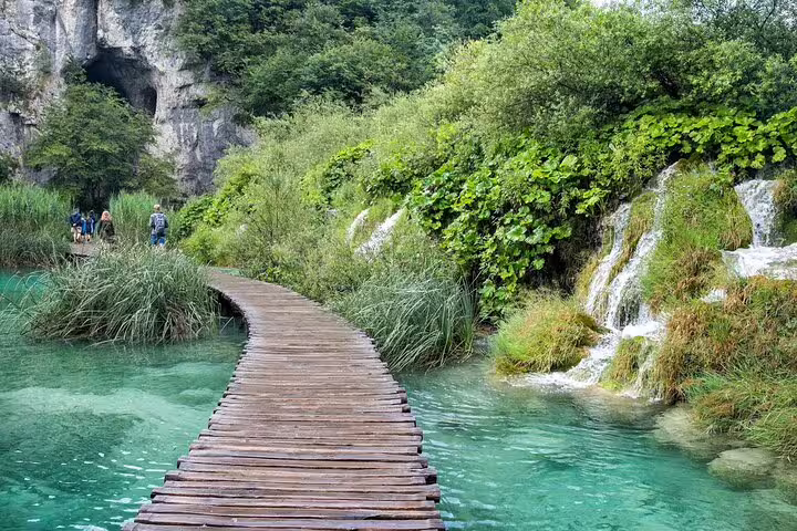Wooden boardwalk over crystal-clear lakes and small cascades at Plitvice Lakes on a private tour from Split