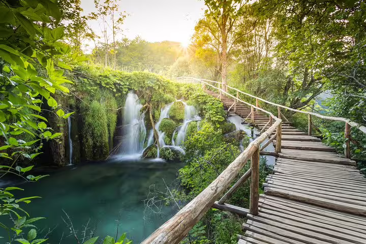 Wooden boardwalk beside waterfalls and turquoise pools on Plitvice Lakes day trip from Zadar and Biograd
