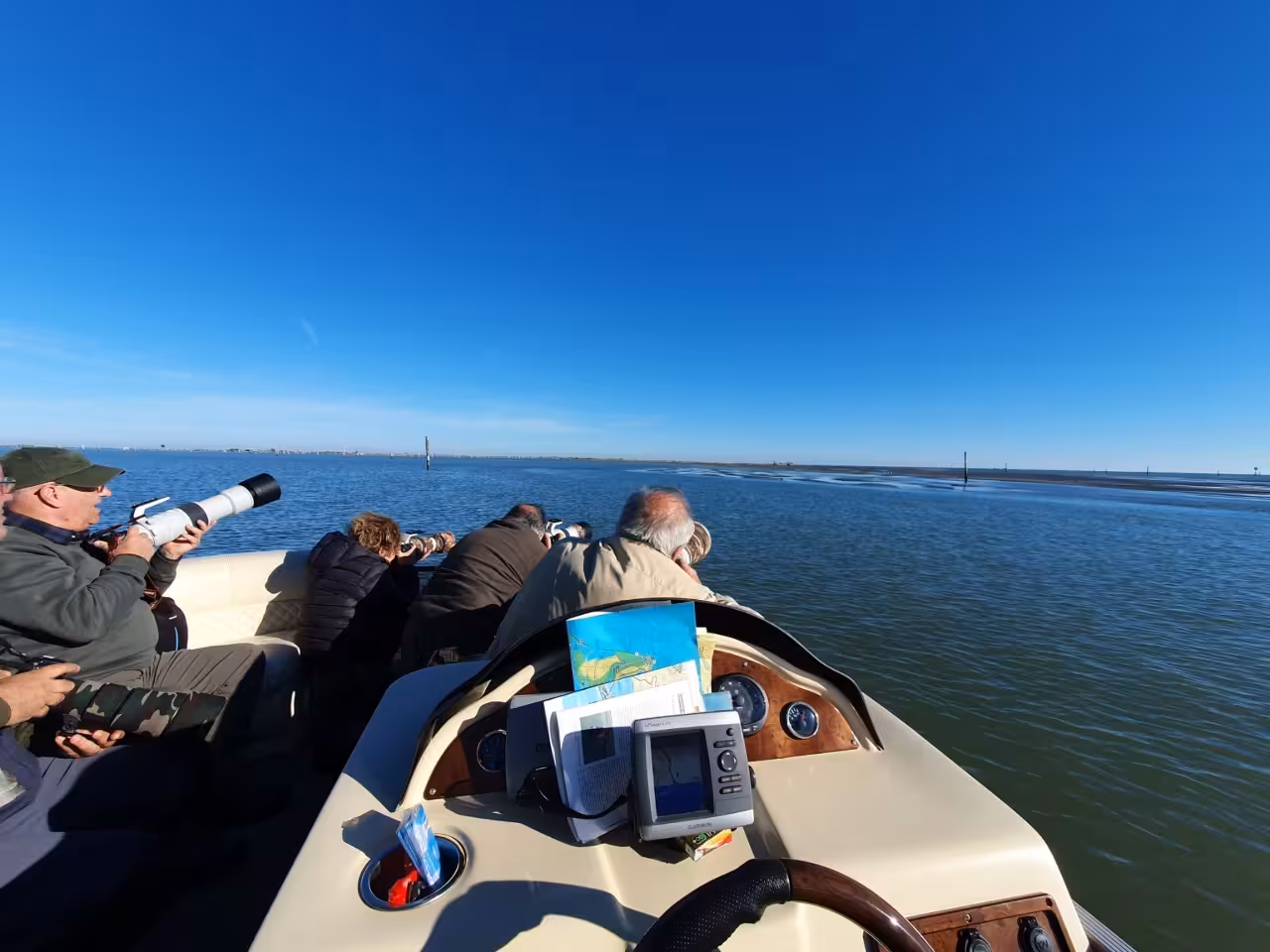 Wildlife photographers on Po Delta lagoon boat tour, scanning sandbars and wetlands near Isola dell’Amore