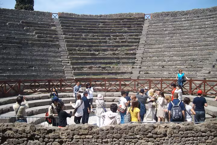 Tourists exploring Pompeii amphitheater, experience included in guided tour with lunch from Sorrento.