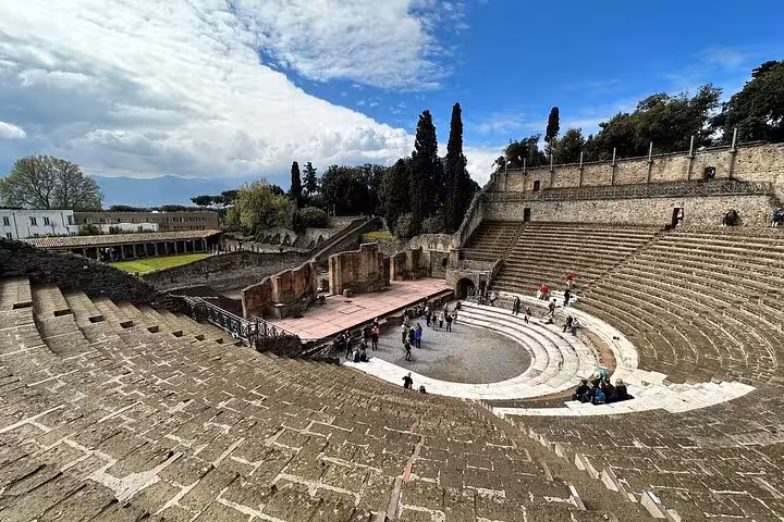 Explore the ancient amphitheater of Pompeii on a guided tour with views of Mount Vesuvius in the background.