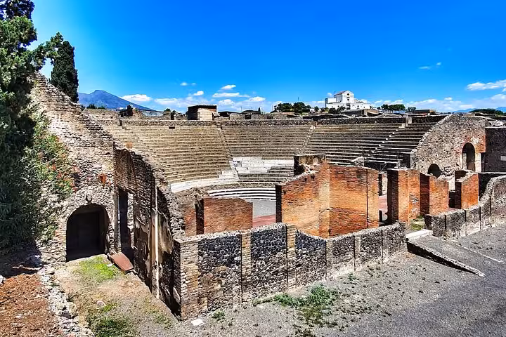 Ancient amphitheater ruins in Pompeii under a clear blue sky, highlighting its historical significance and architecture.