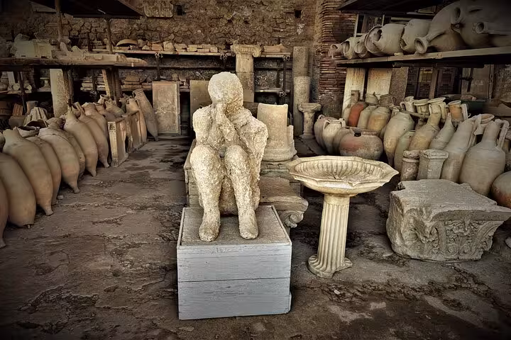 Ancient artifacts and a plaster cast of a victim displayed in Pompeii, highlighting the city's preserved history.