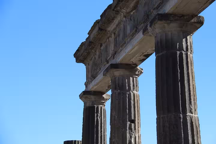 Ancient columns under a bright blue sky at Pompeii, part of the private transfer tour from Rome.