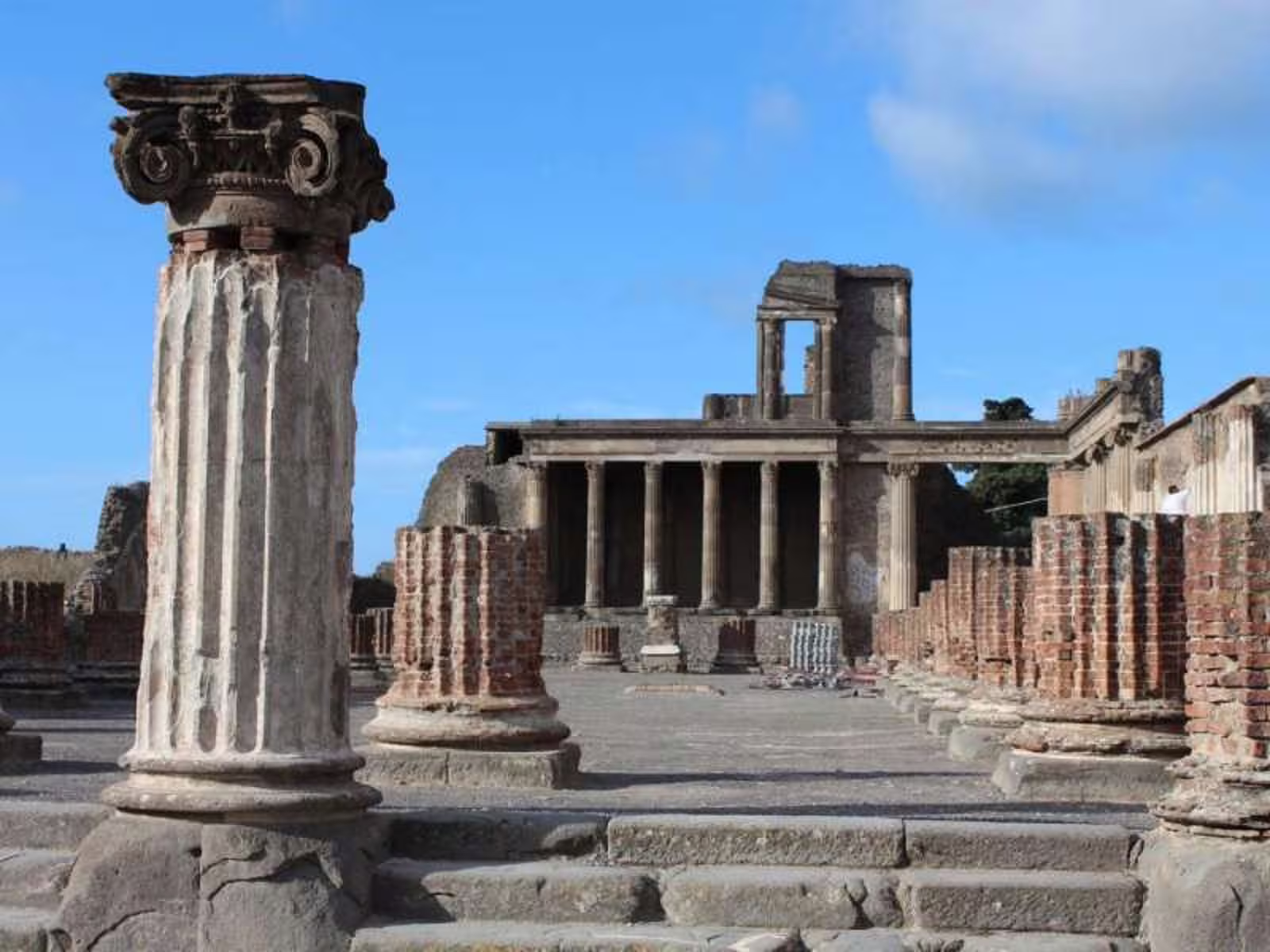 Ancient columns and temple ruins in Pompeii under blue skies, visited on a semi private afternoon tour from Rome