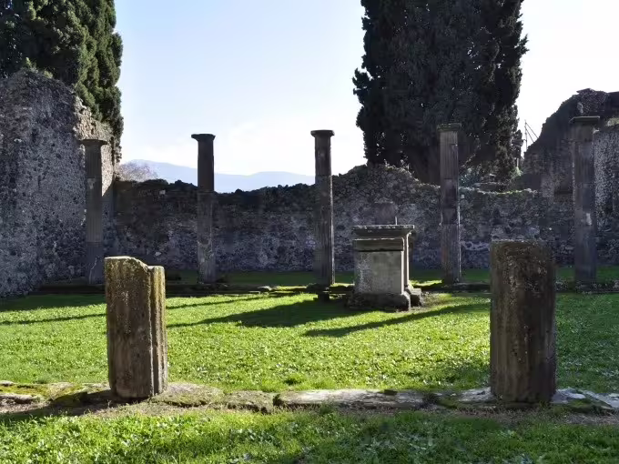 Ancient Pompeii courtyard with stone columns and altar, featured stop on Pompeii and Herculaneum group tour from Naples