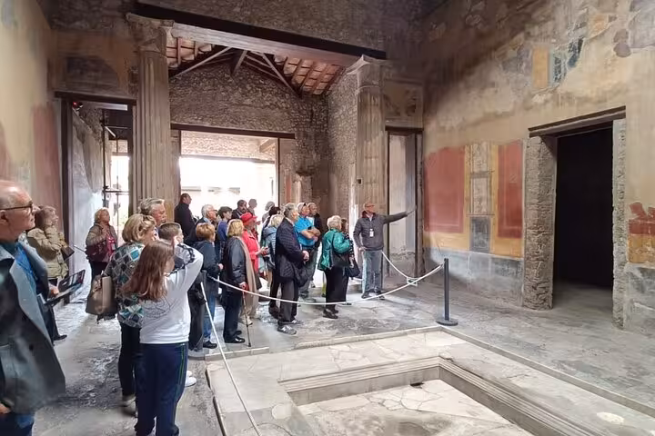 Tourists explore ancient frescoes inside a preserved room at the archaeological site of Pompeii.