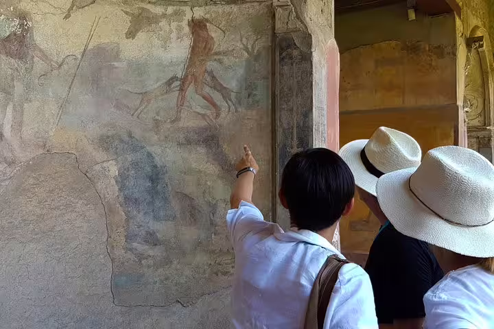 Tourists admire ancient frescoes during a guided tour of Pompeii from Sorrento, showcasing rich historical art.