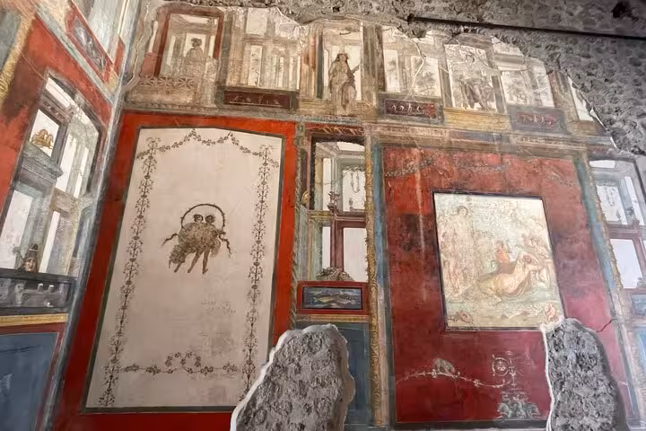 Intricate frescoes adorn the walls of a historic building in Pompeii, showcasing ancient art and vibrant colors.