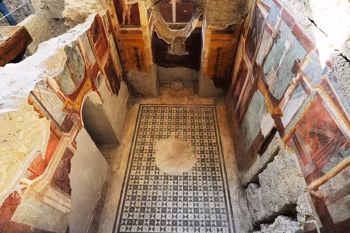 Ancient frescoes and mosaic floors in a well-preserved room at the archaeological site of Pompeii, Italy.