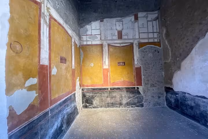 Room adorned with colorful ancient frescoes in Pompeii, illustrating Roman architectural and artistic heritage.