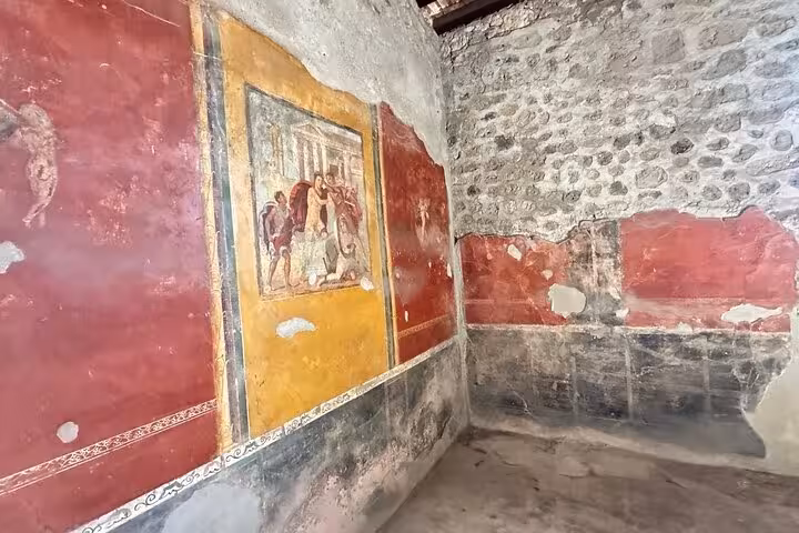 Ancient frescoes adorn the walls of a preserved room in Pompeii, showcasing vibrant Roman art and history.