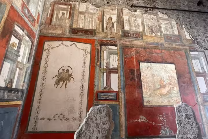 Ancient frescoes with vibrant colors in a preserved room in Pompeii, showcasing Roman artistry and history.