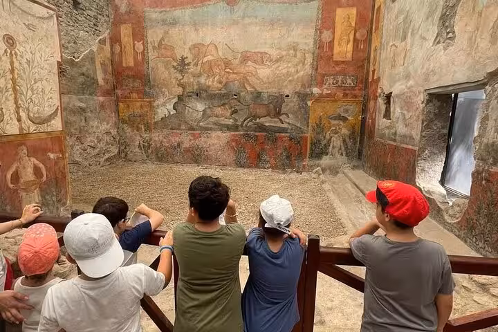 Visitors admire ancient frescoes in Pompeii on a guided day trip from Sorrento, highlighting historic art and culture.