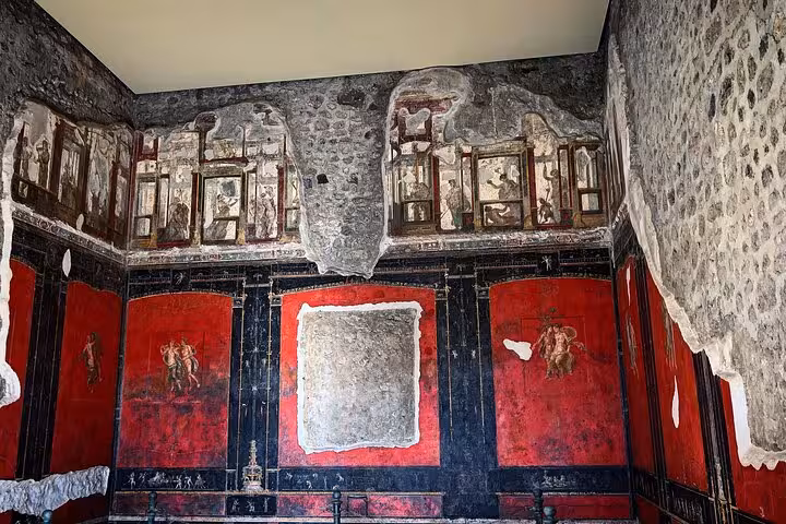 Ancient frescoes with vibrant colors in a room at Pompeii, highlighting the cultural aspect of the Vesuvius tour.