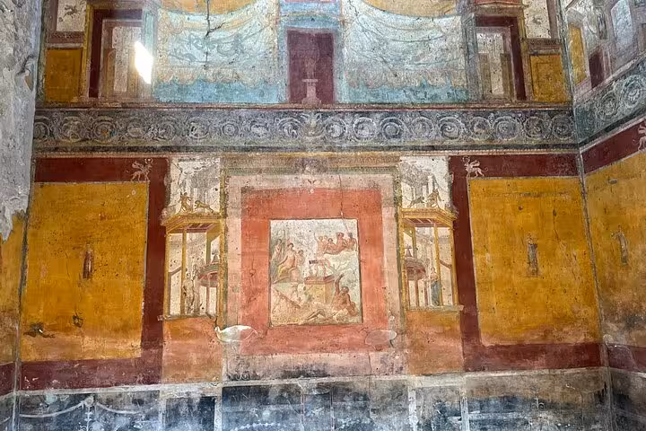 Ancient frescoes with vibrant colors adorn the walls of a historic building in Pompeii, showcasing intricate artistry.
