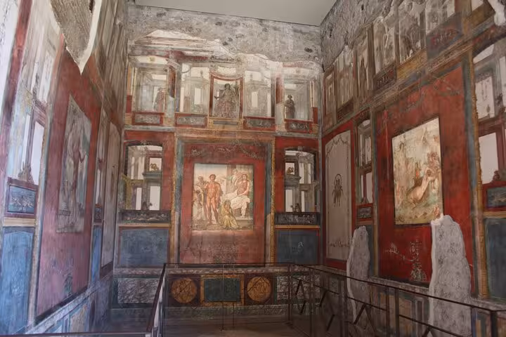 Intricate frescoes in a well-preserved room in Pompeii, showcasing ancient Roman art on a guided day trip from Rome.