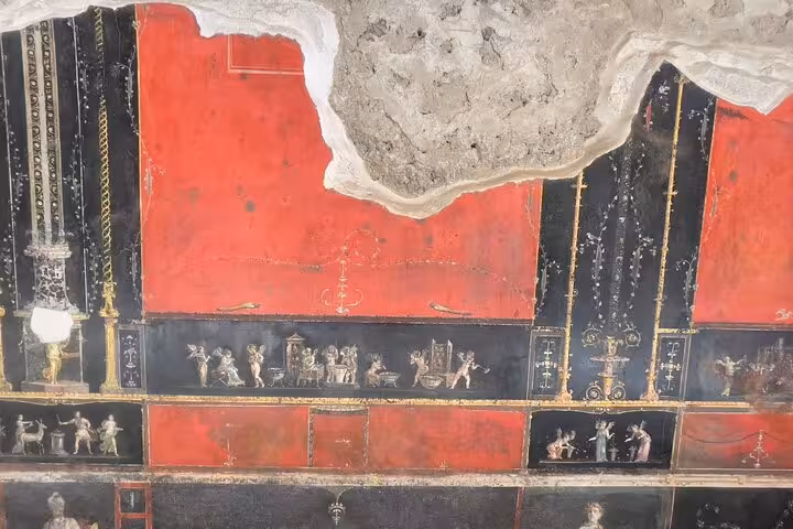 Vibrant frescoes depicting ancient Roman figures on a red and black background in Pompeii's historic ruins.