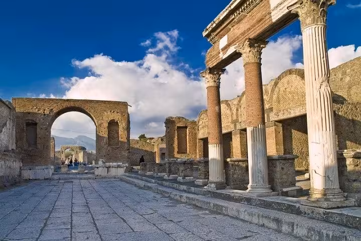 The ancient ruins of Pompeii with majestic columns and arches under a clear blue sky.