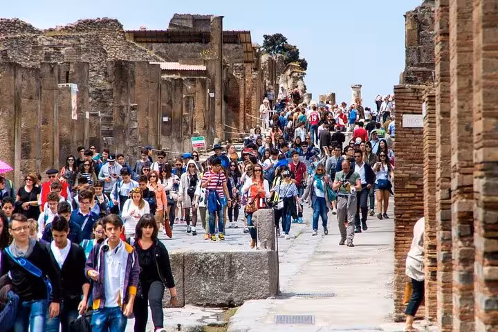 Experience the vibrant atmosphere of Pompeii with a crowd of tourists exploring the ancient ruins on a guided private tour.