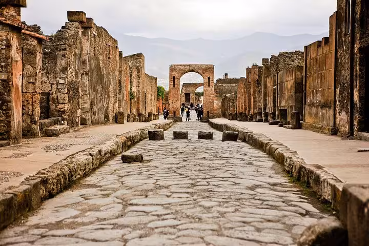 Explore the ancient stone streets of Pompeii on a private tour, showcasing its well-preserved ruins and historical arches.