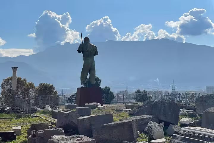 Statue overlooking ancient ruins in Pompeii with scenic mountain backdrop on a guided tour with skip the line entry.