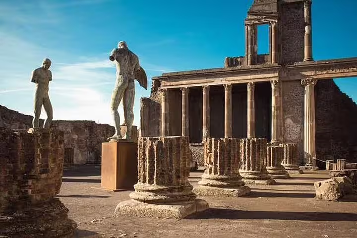 Ancient temple ruins and statues in the archaeological site of Pompeii, visited on the Sorrento Pompei Vesuvio day tour