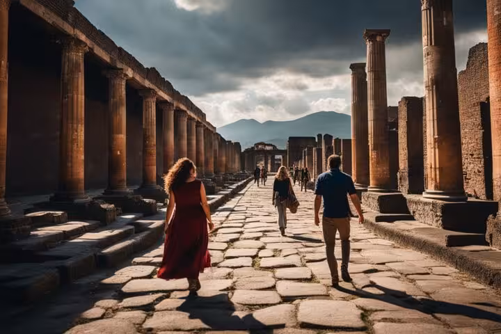 Tourists walking through the ancient ruins of Pompeii, showcasing historic columns and pathways under dramatic skies.