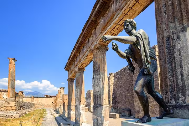 Admire the ancient statues and architectural marvels of Pompeii with Mount Vesuvius in the distance on a guided tour.