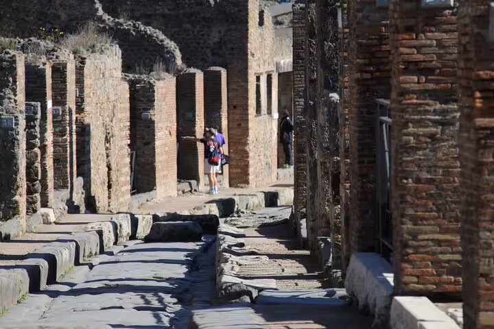 Visitors walking through the ancient stone streets of Pompeii on a guided tour.