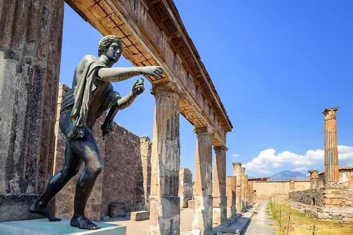 Bronze statue and colonnade in Pompeii ruins, featured on private tour from Naples to Sorrento and Amalfi