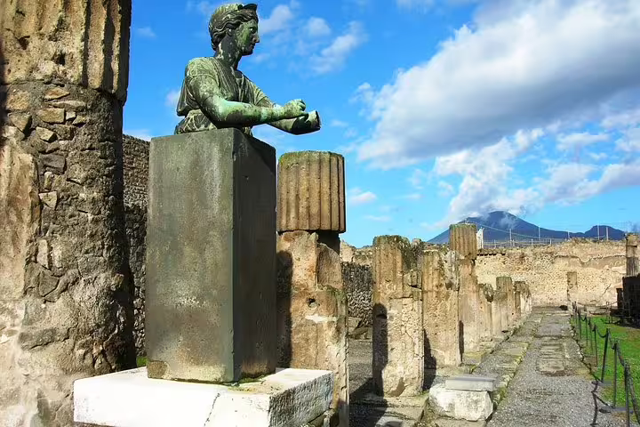 Bronze statue among Pompeii ruins with Mount Vesuvius backdrop on a Naples to Pompeii half-day group tour