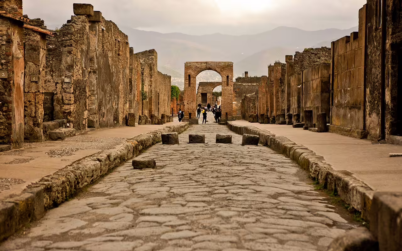 Ancient cobblestone street in Pompeii with archway and Vesuvius views on VIP small-group tour