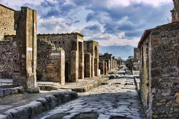 Ancient cobblestone street in Pompeii ruins with Mount Vesuvius view on low cost Pompeii tour from Naples