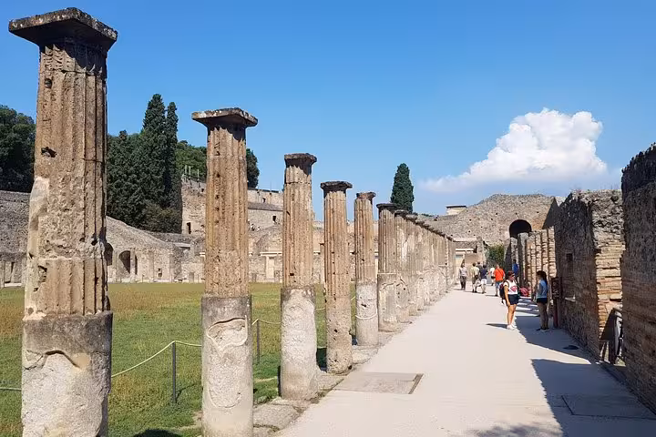Ancient Pompeii colonnade walkway under blue sky, cultural stop on 6-day private Rome to Amalfi Coast tour