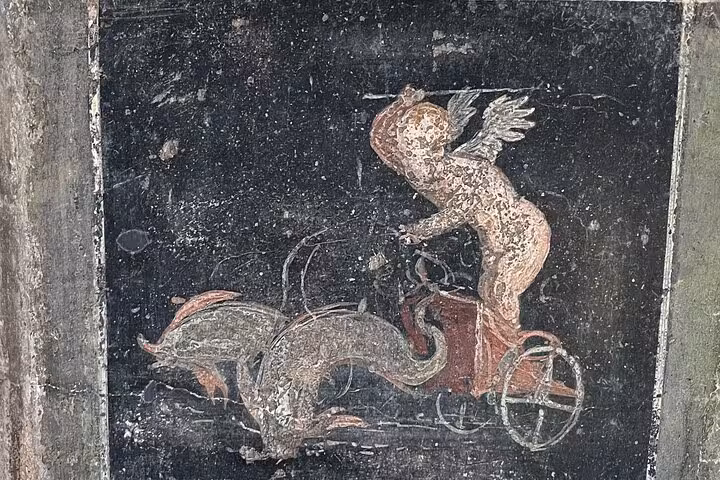 Ancient fresco of Cupid riding dolphins in Pompeii, seen on a guided tour and wine tasting from Positano.