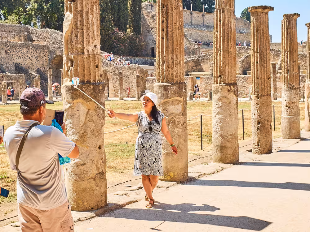 Tourists capturing memories among ancient columns on the Pompeii express prestige tour from Rome by minivan.