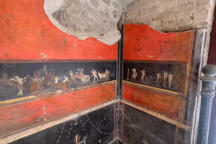 Vibrant red and black fresco in Pompeii showcasing Roman life, featured on the Pompeii & Vesuvius tour from Positano.