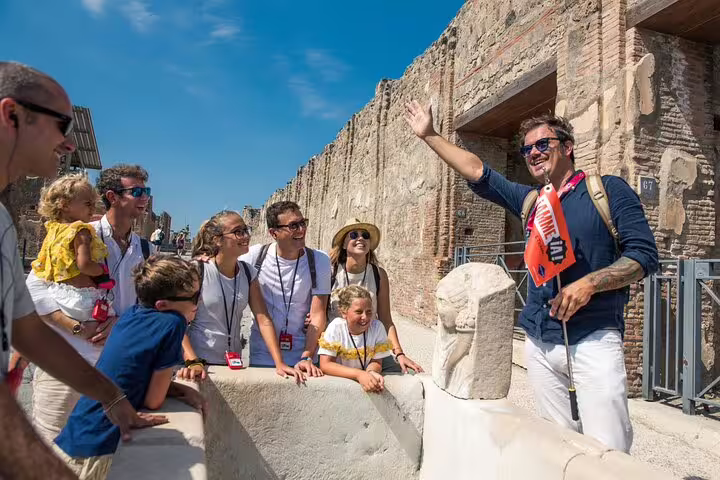 Tour guide engaging with visitors during a skip-the-line Pompeii guided tour from Sorrento, exploring ancient ruins.