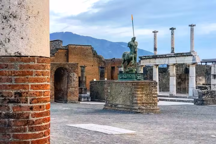 Explore Pompeii's ancient ruins with a guided tour from Sorrento Coast, featuring iconic statues and historic architecture.